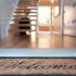 Close up of a welcome mat in front of an inviting house. Focus on foreground Close up of a welcome mat in front of an inviting house. Focus on foreground